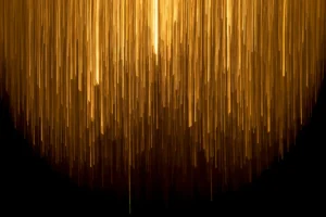 Luces verticales doradas descendiendo en un patrón abstracto sobre fondo negro, simbolizando la innovación y creatividad en el diseño de experiencia de usuario.